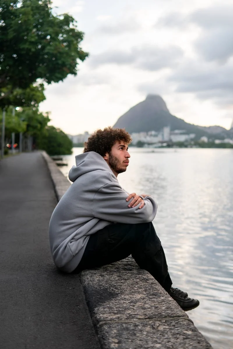 Hombre reflexiona sentado junto a un lago tras el fin de una relación