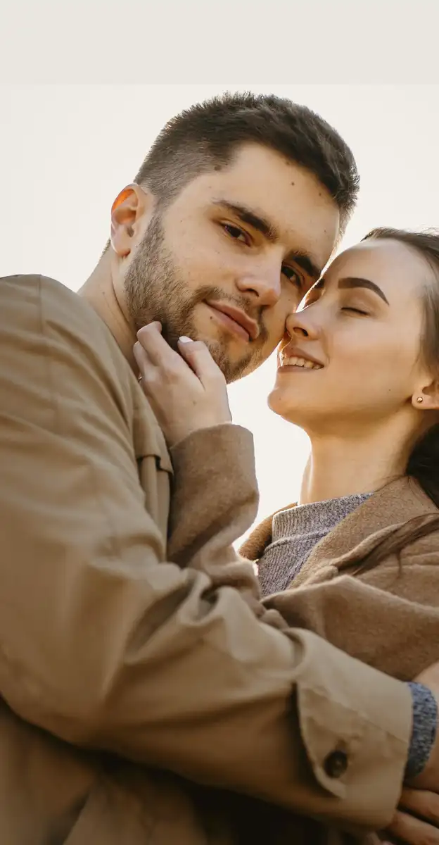 Pareja se abraza sonriente al aire libre entre pastizales dorados, el vínculo que la terapia de pareja ayuda a fortalecer